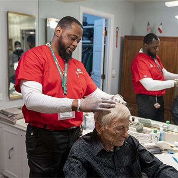 Caregiver fixing elderly man's hair