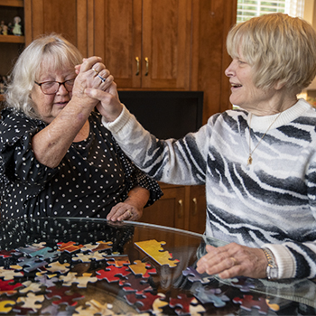 Caregiver and elderly woman working on a puzzle