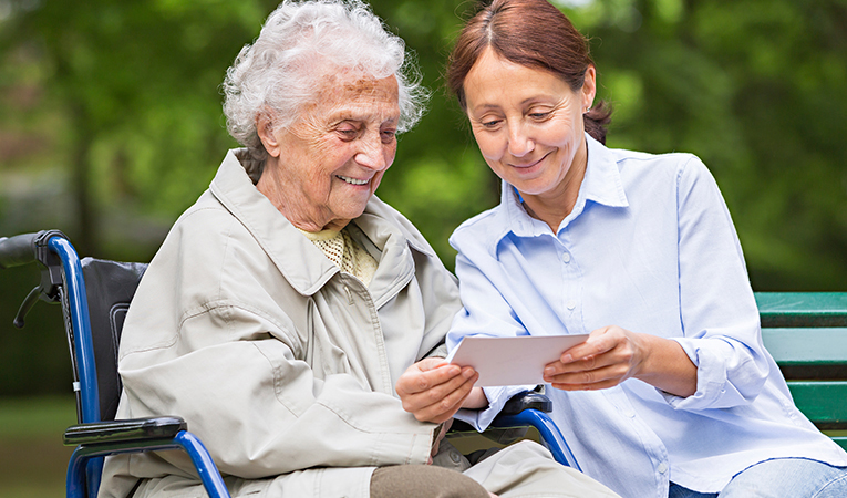 Caregiver and elderly woman looking at photographs