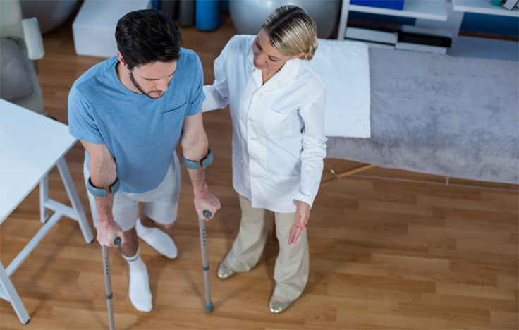 Caregiver helping a man on crutches