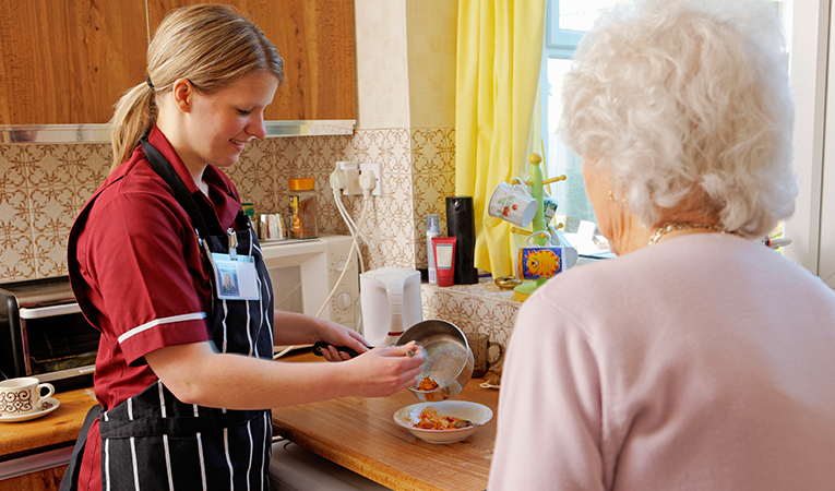 Caregiver making lunch for elderly woman